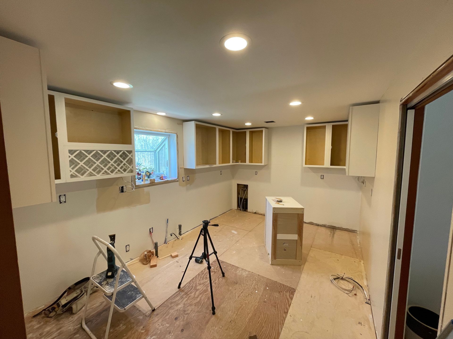 A kitchen under construction with a tripod in the middle of the room.