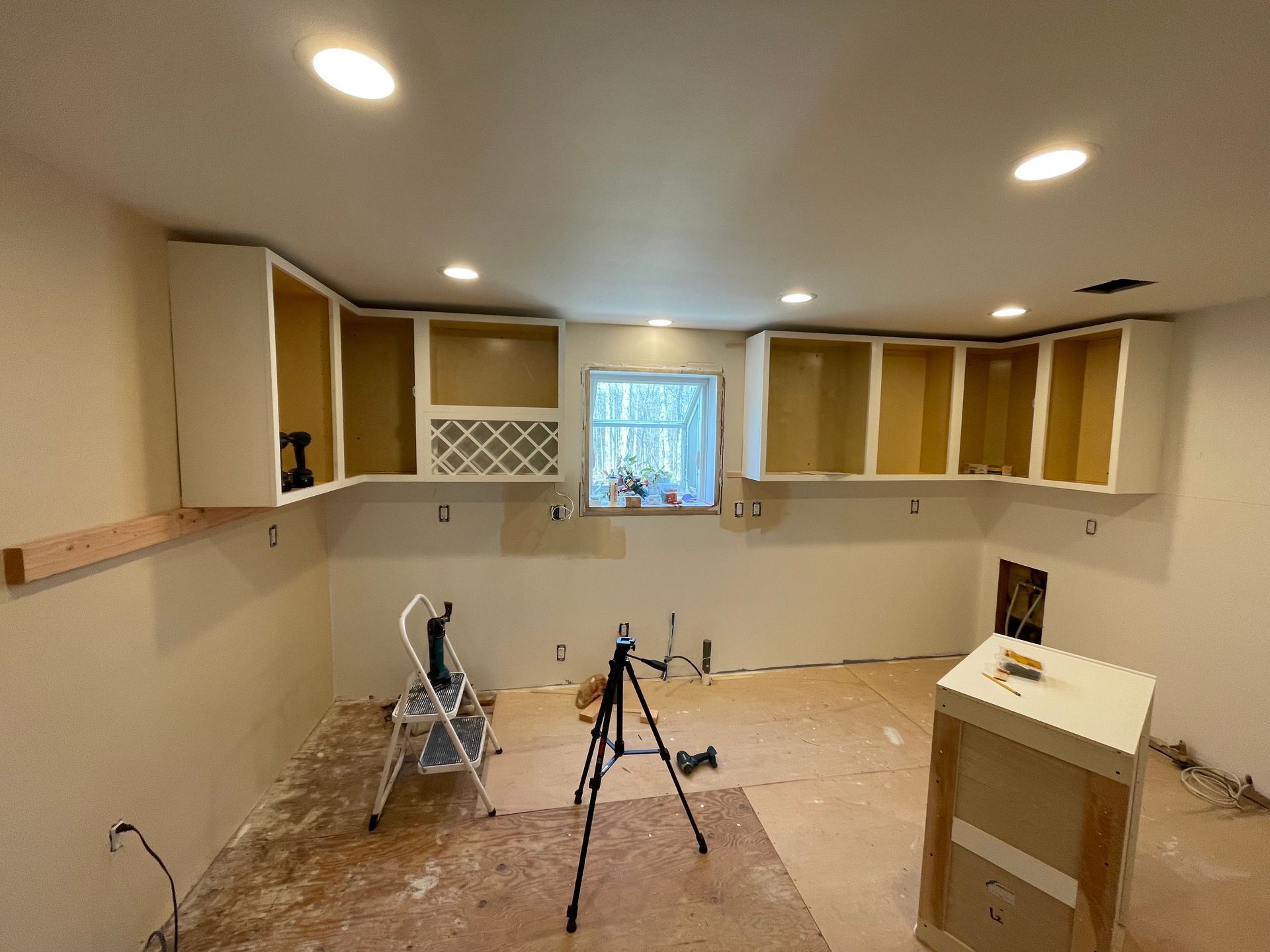 A kitchen under construction with a ladder and a tripod.