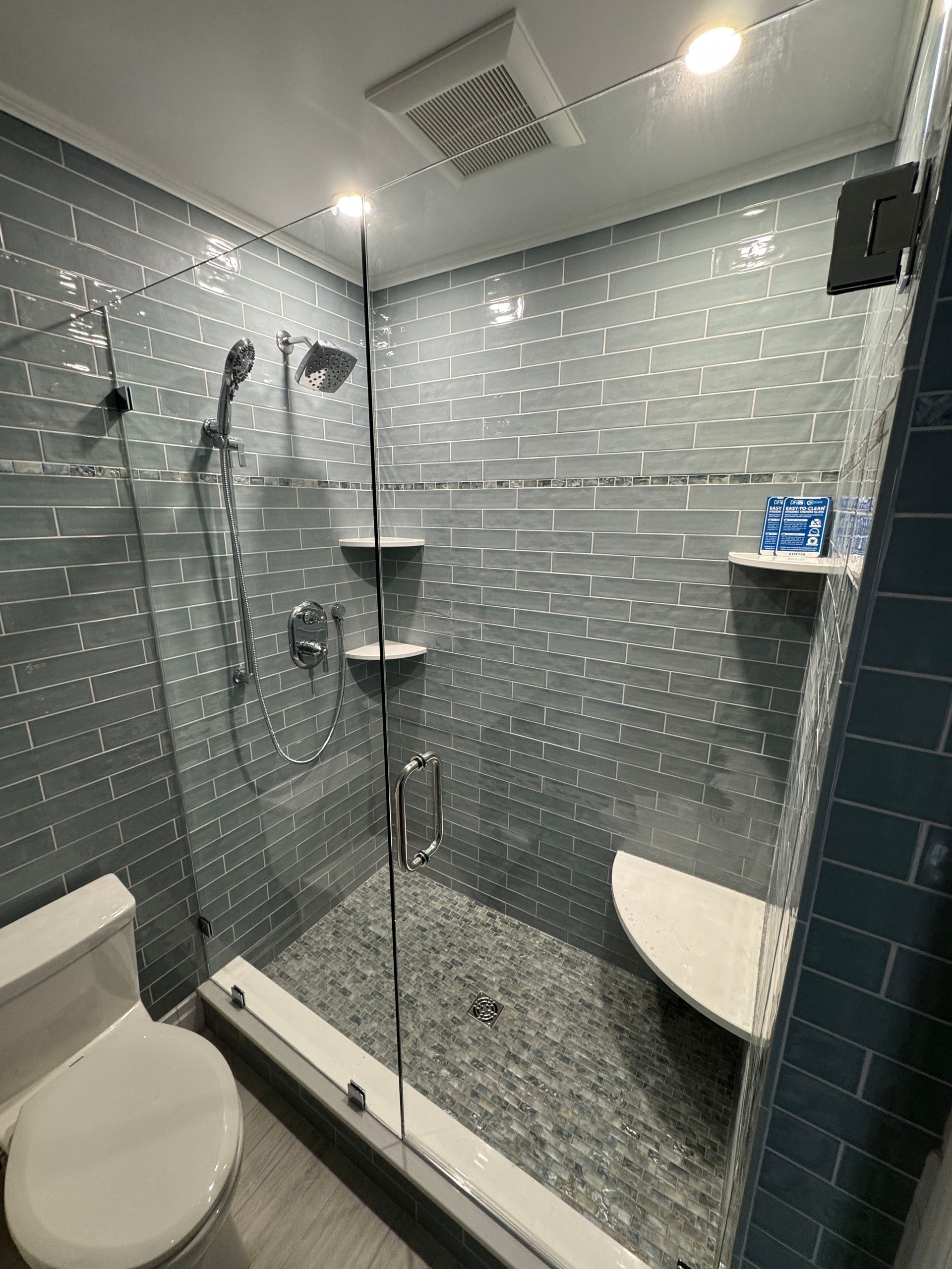 A bathroom with a toilet and a walk in shower with a glass door.