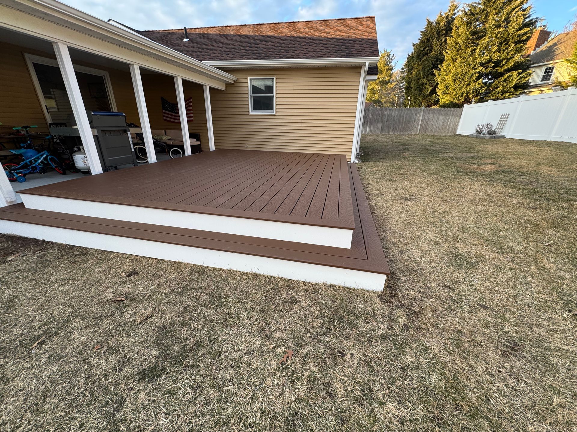 A wooden deck with stairs is in the backyard of a house.