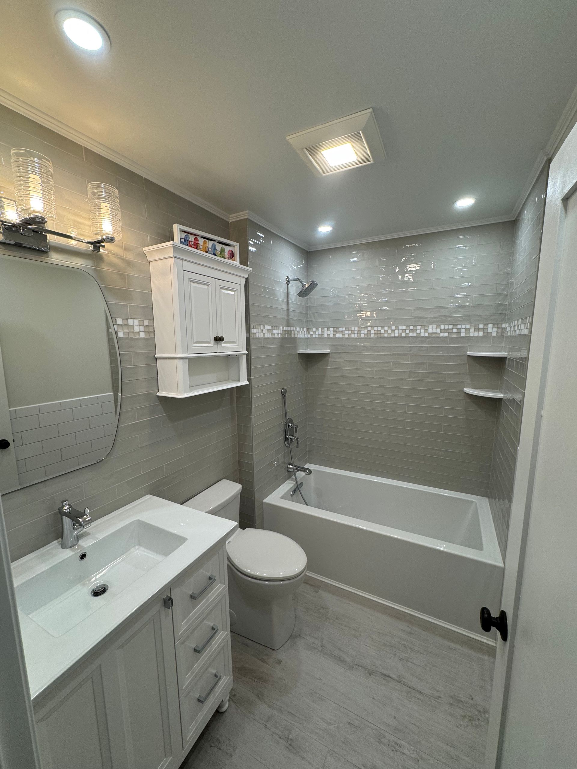 A bathroom with a toilet , sink , tub and mirror.