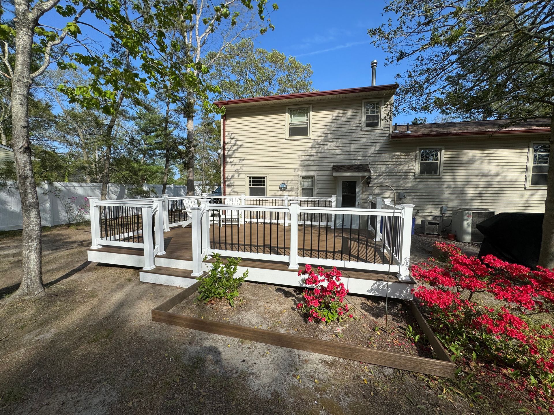 A house with a large deck and a white fence
