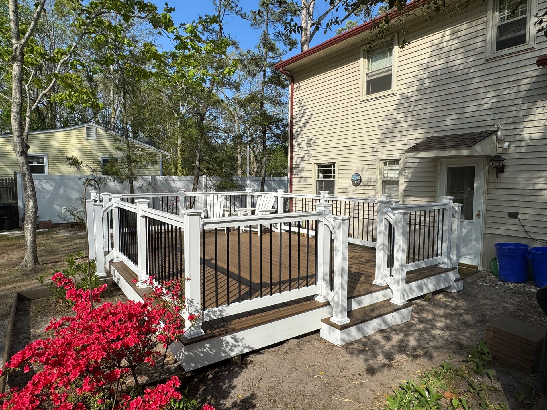 A white house with a large deck in front of it.