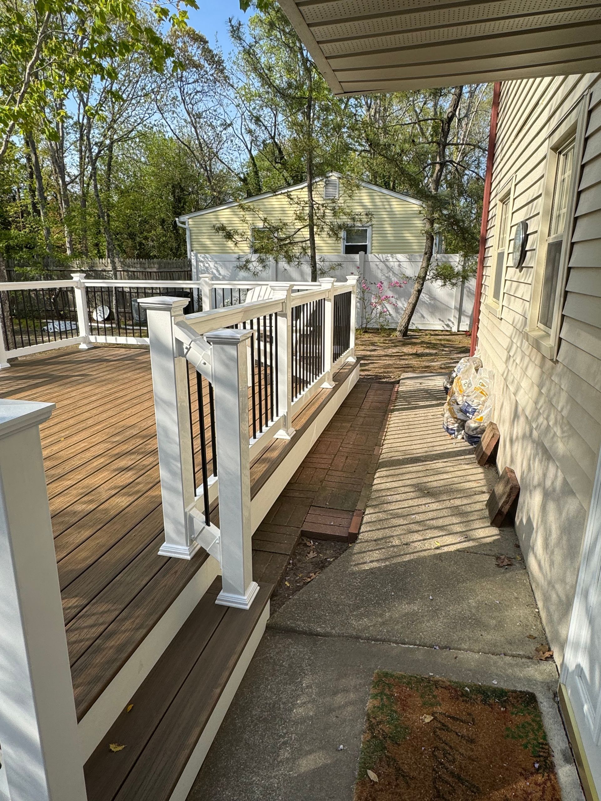 A wooden deck with a white railing next to a house.