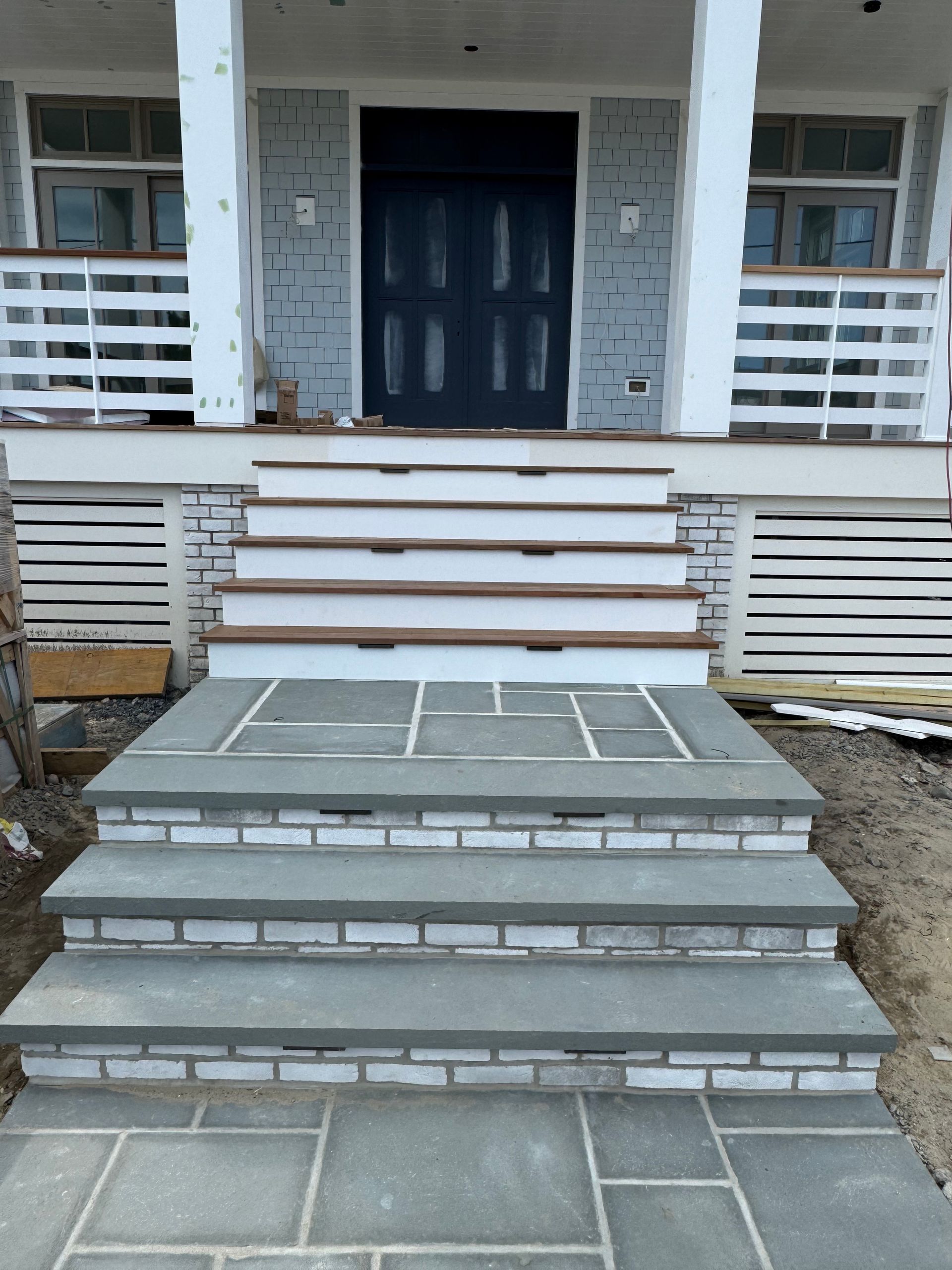 A set of stairs leading up to a porch with a blue door