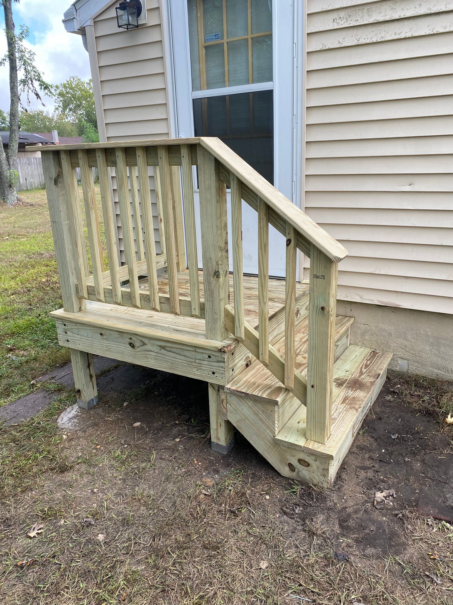 A wooden deck with stairs leading to the door of a house.