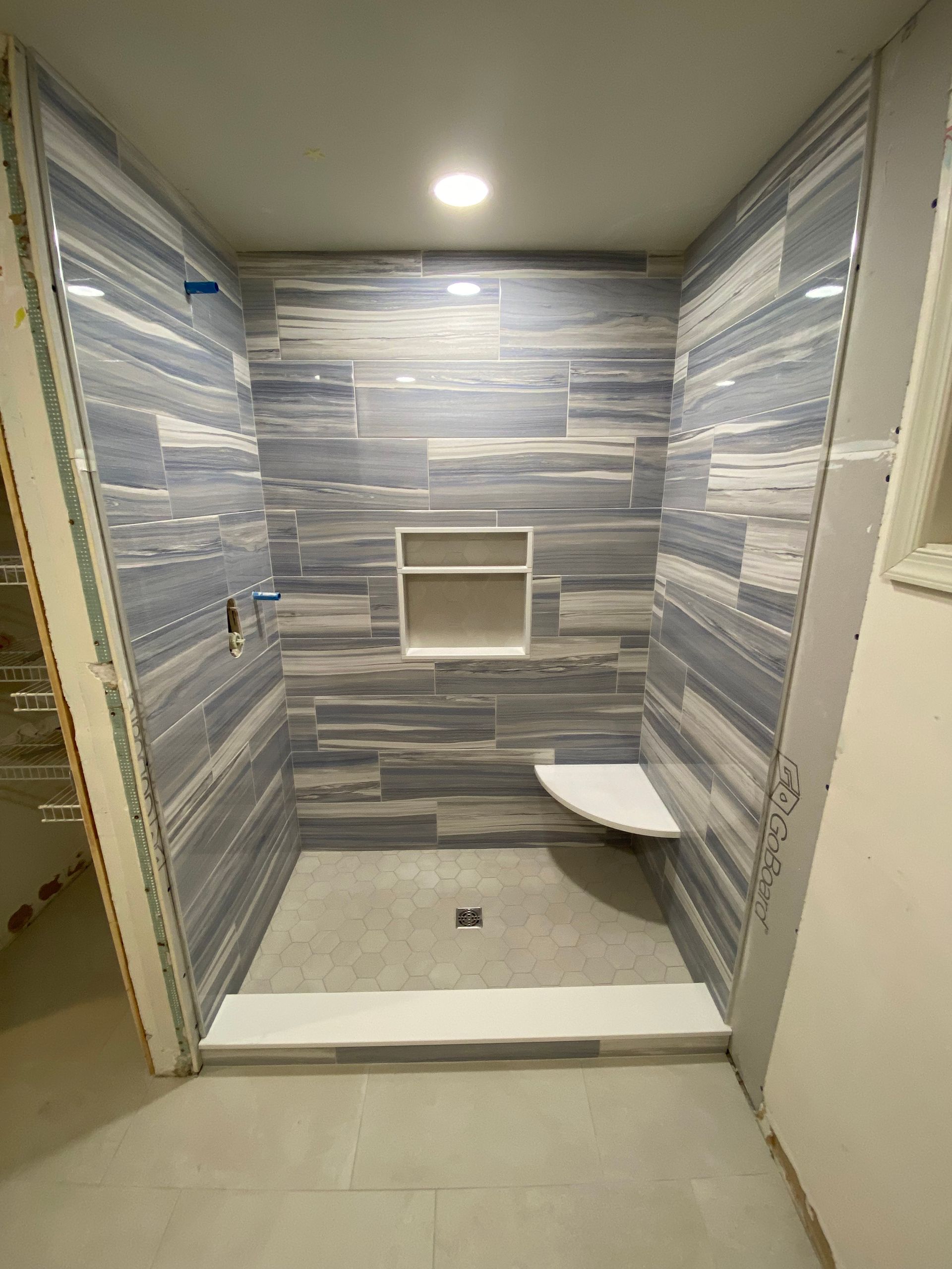 A bathroom with blue and white tiles and a walk in shower.