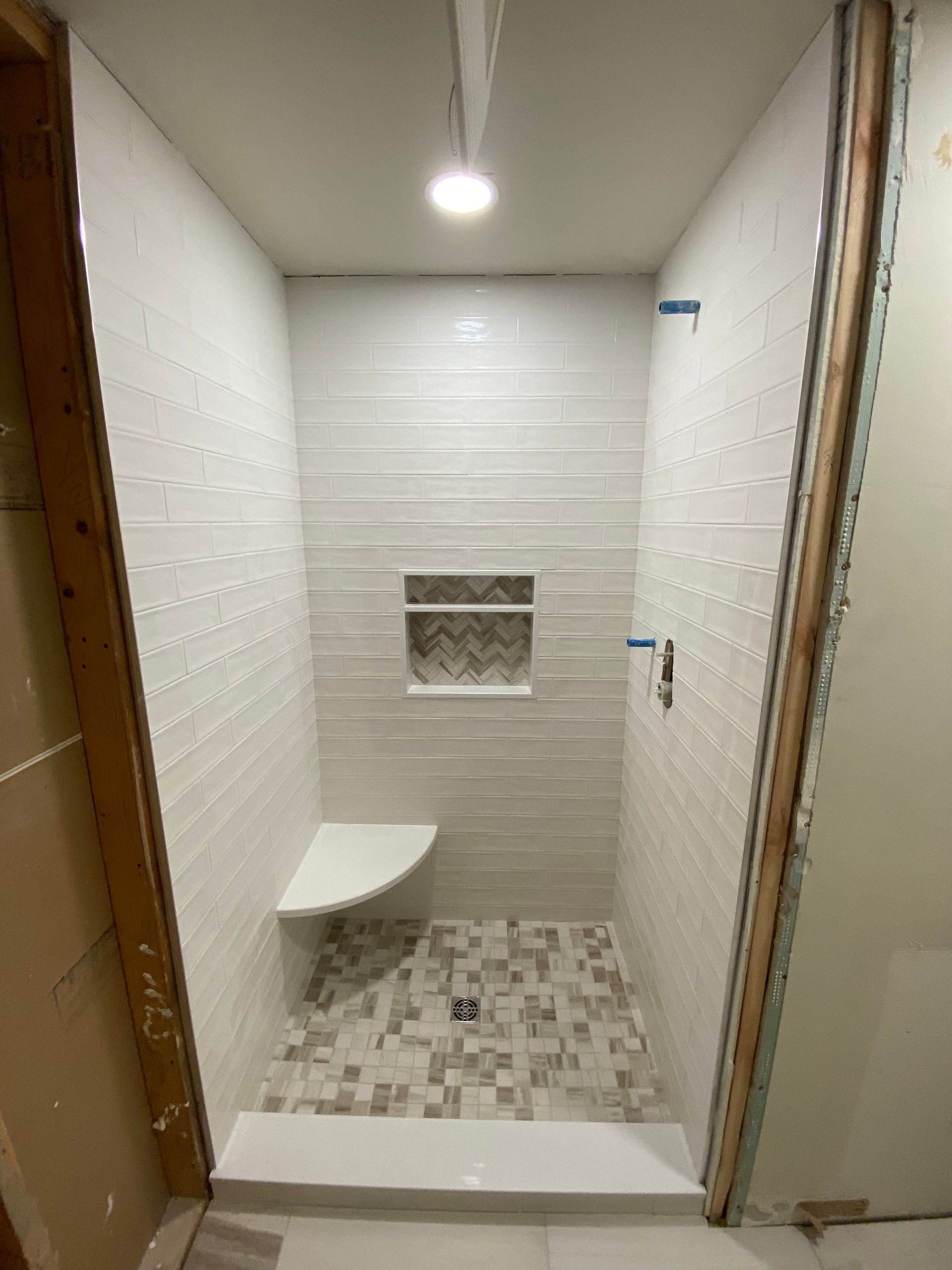 A bathroom with a shower stall and a bench.
