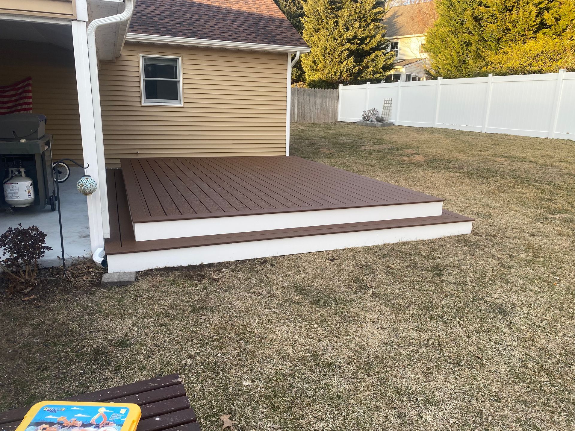 A deck with stairs leading up to it is in the backyard of a house.
