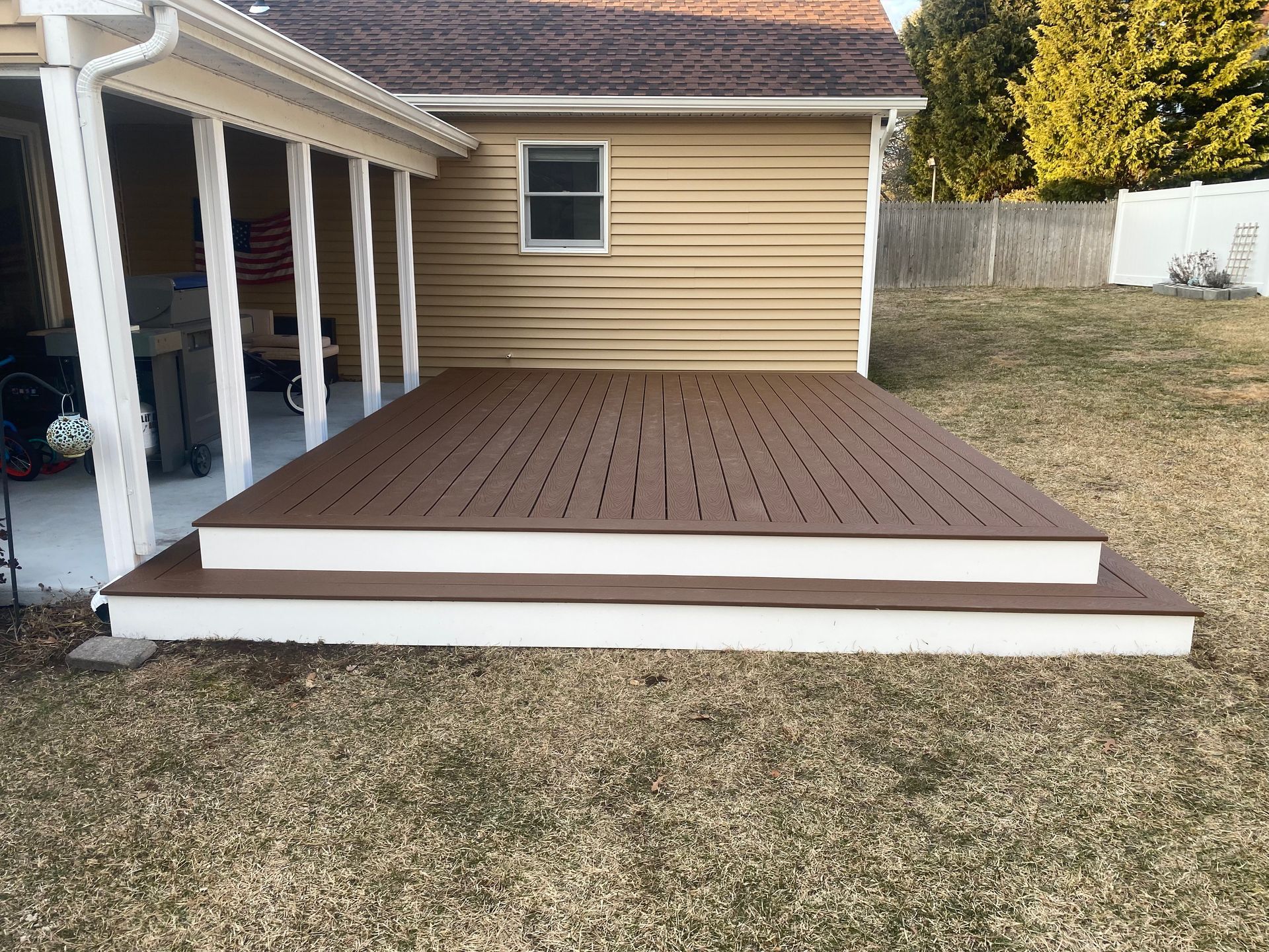 A wooden deck with stairs is in the backyard of a house.