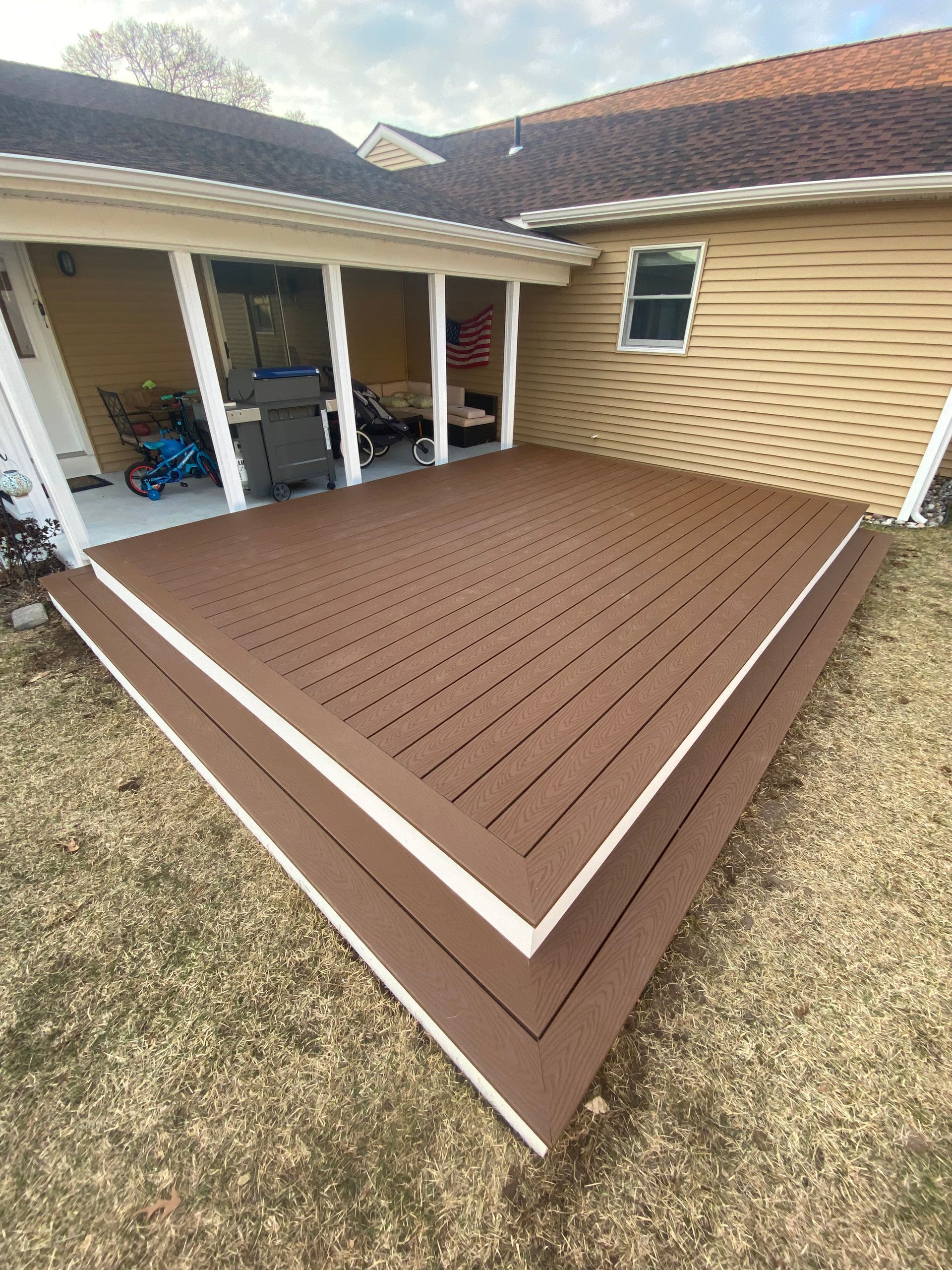 A wooden deck with a white border is sitting in front of a house.