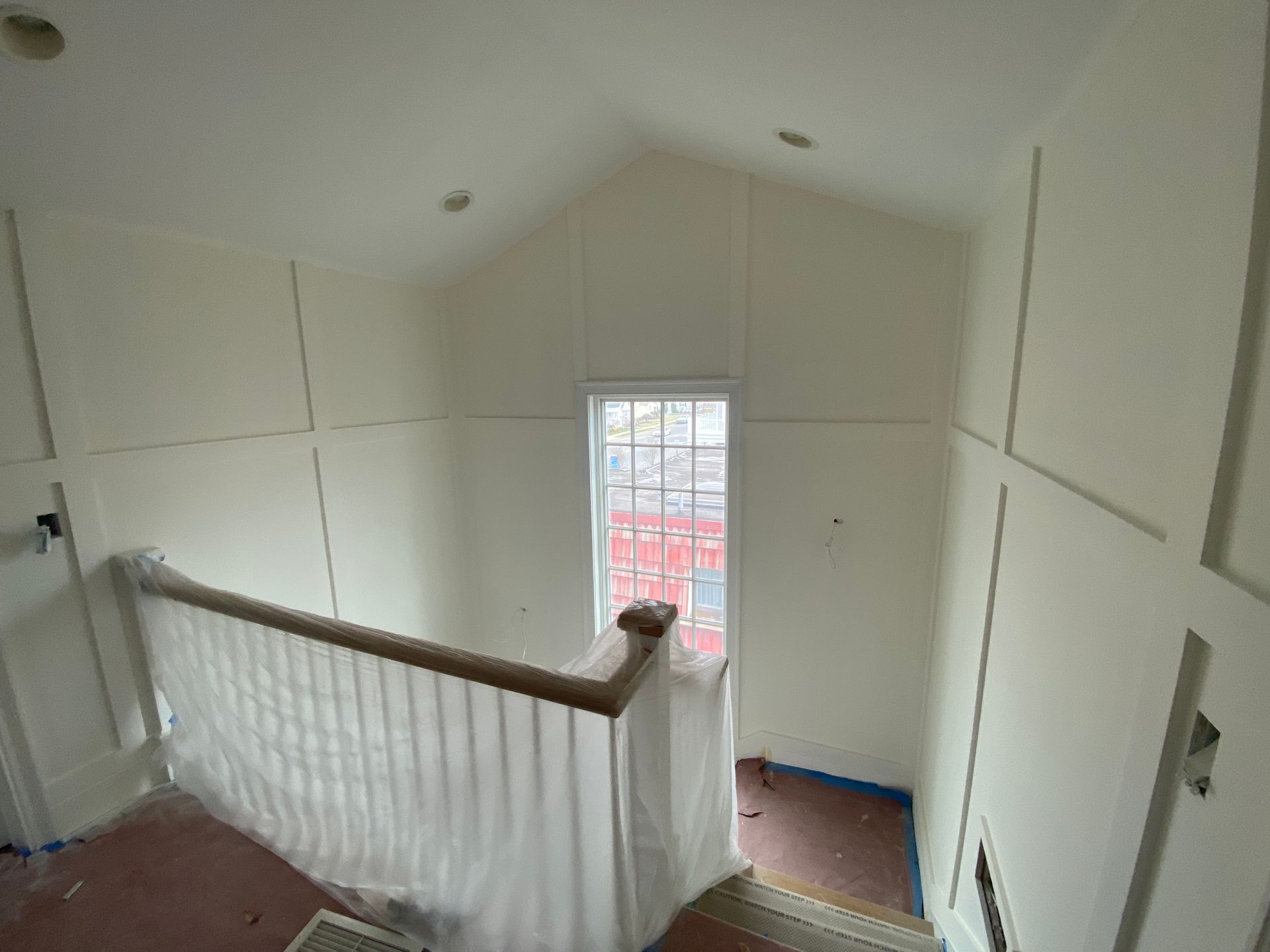 An aerial view of a staircase with white walls and a window.