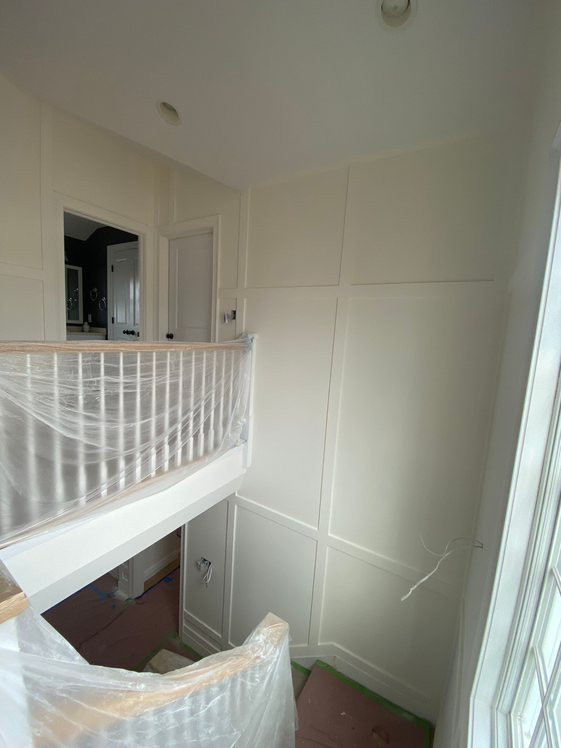 A room with a staircase and a railing covered in plastic.