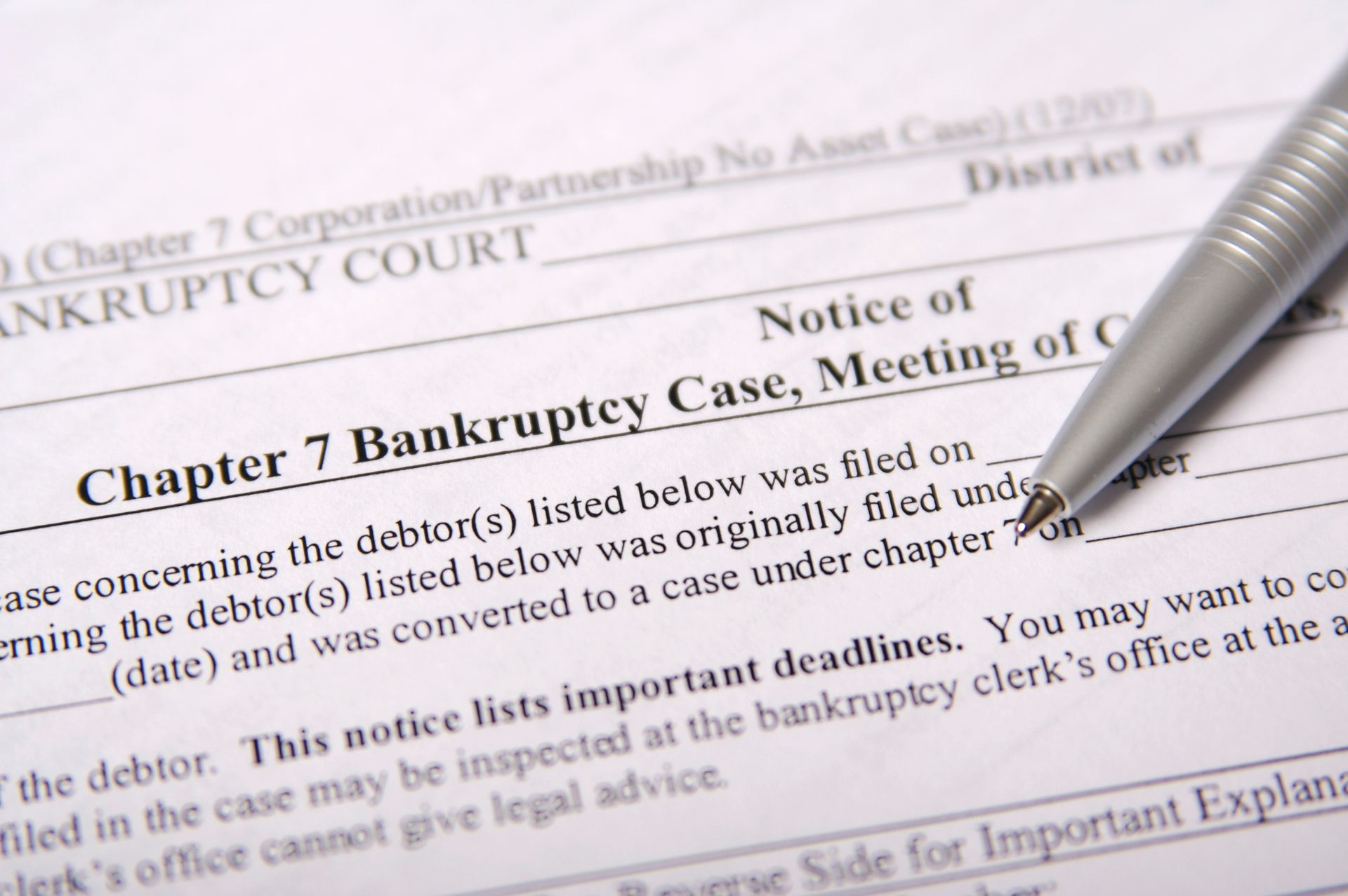 United States legal document with a pen on top focused on a Notice for Chapter 7 bankruptcy.