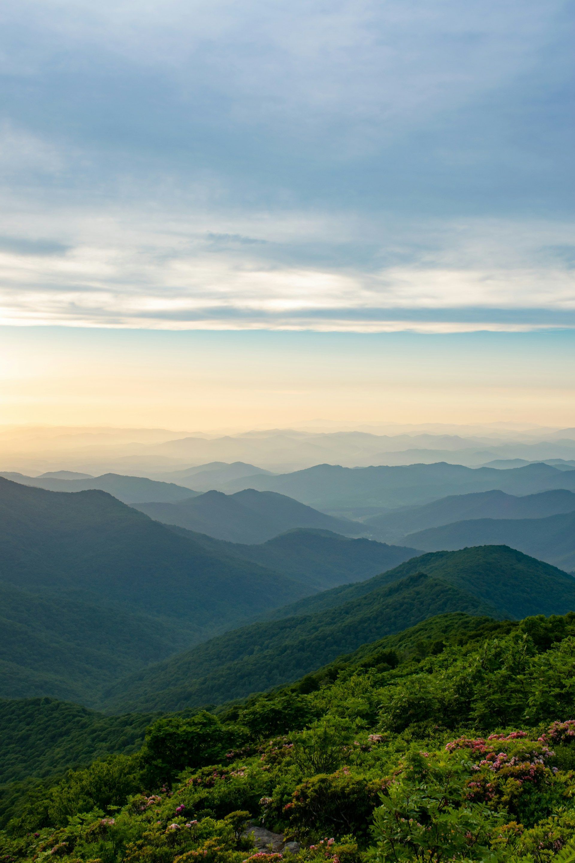 Green mountain range with a blue and yellow sky, capturing a scenic view.