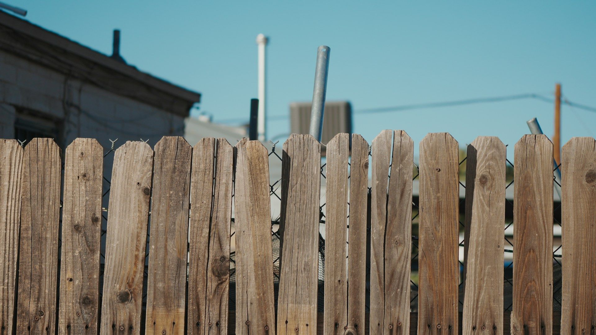 Wooden fence in front of a building, blue sky.