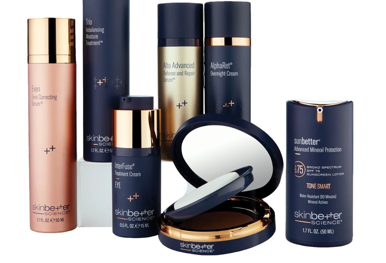 Collection of dark blue and rose gold skincare product bottles and compacts.
