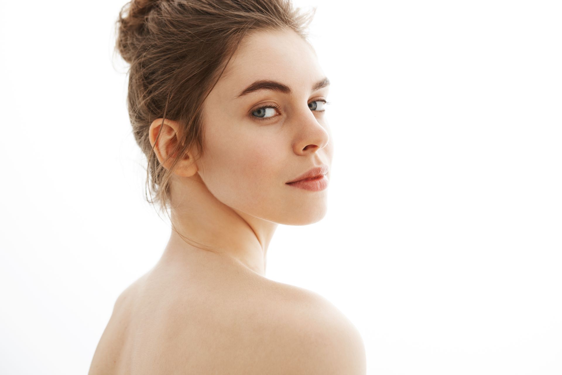 A woman without a shirt is looking over her shoulder at the camera.
