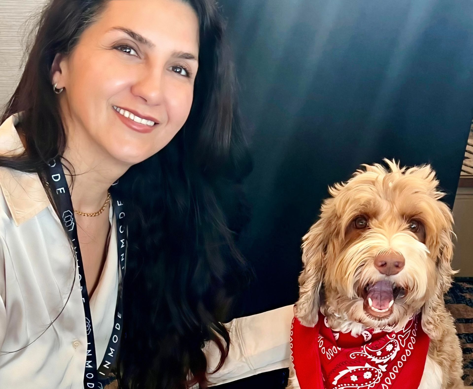 A woman is sitting next to a small brown dog.
