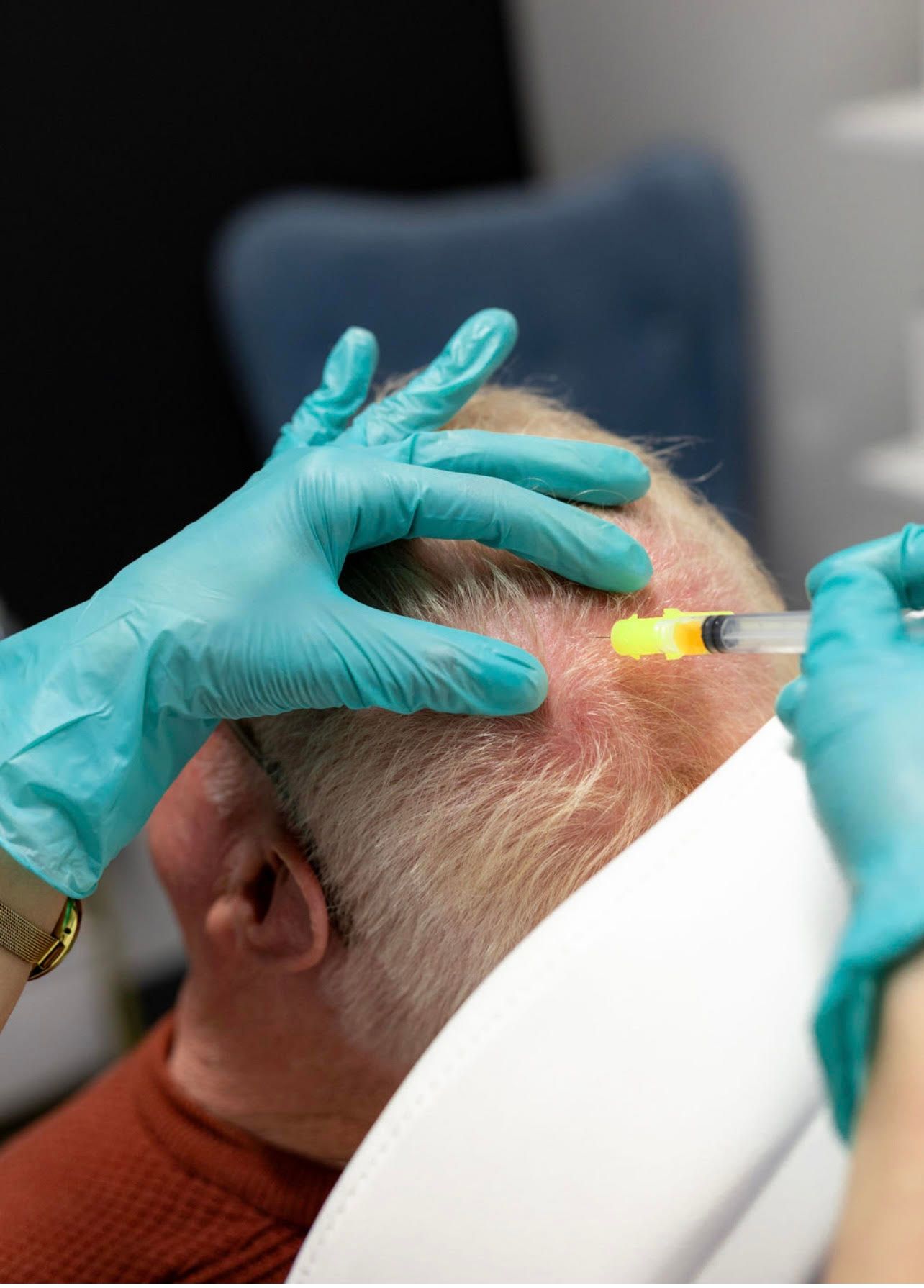 A man is getting an injection in his head by a doctor.