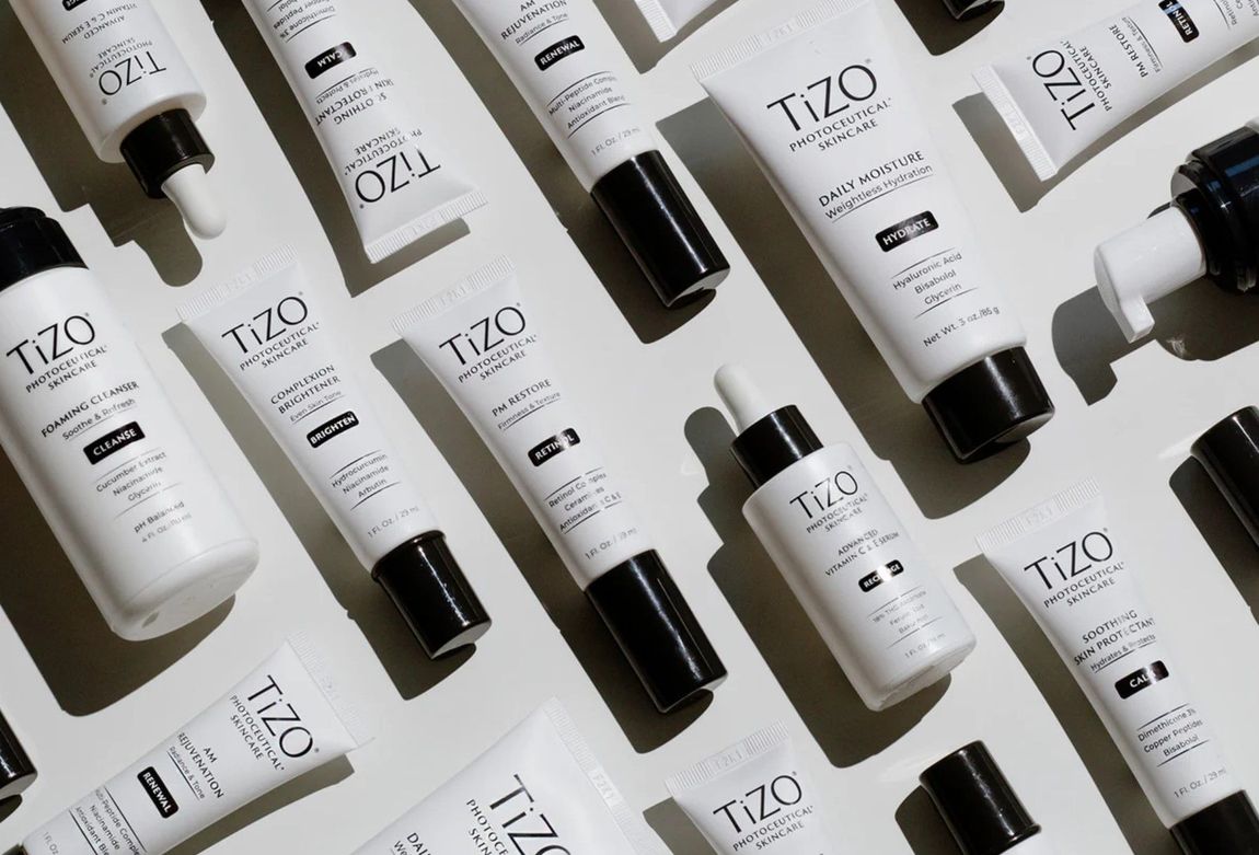 A bunch of bottles of tizo cosmetics are laying on a table.