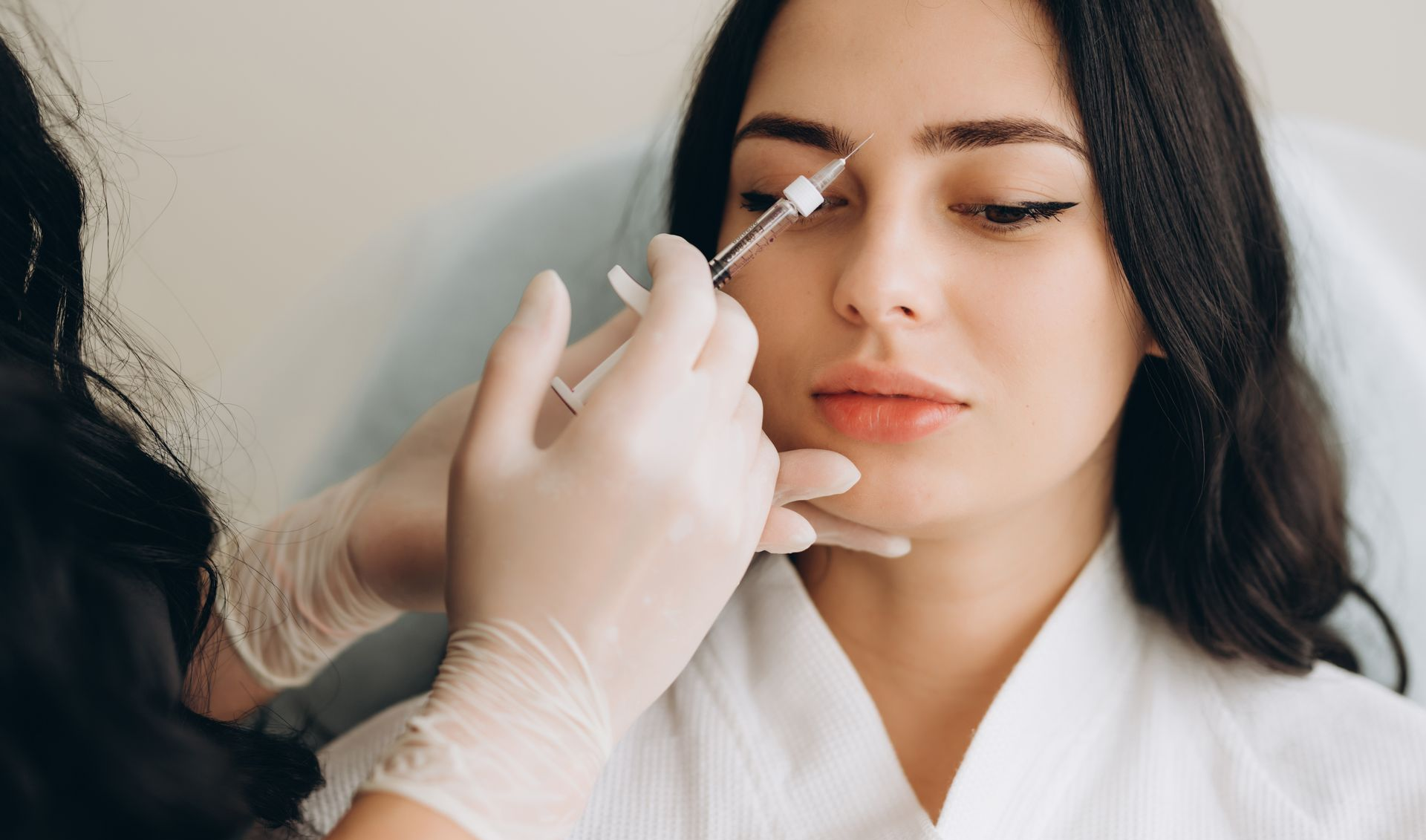A woman is getting a botox injection in her forehead.