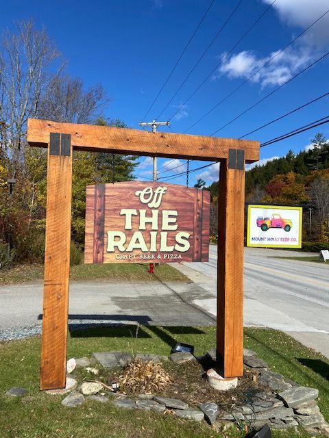 A wooden sign that says off the rails on it