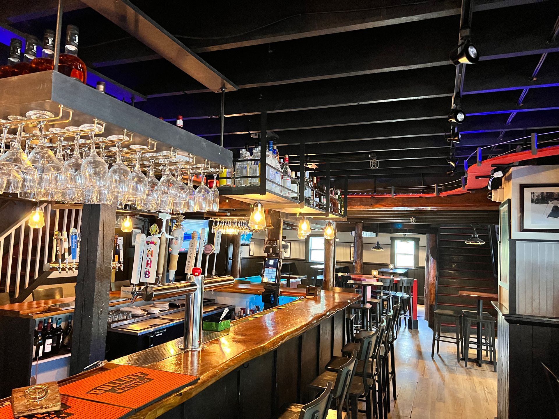 A bar with a lot of wine glasses hanging from the ceiling.