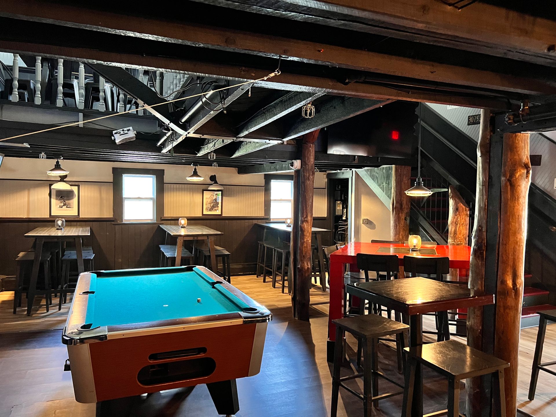 A pool table is in the middle of a room with tables and chairs.