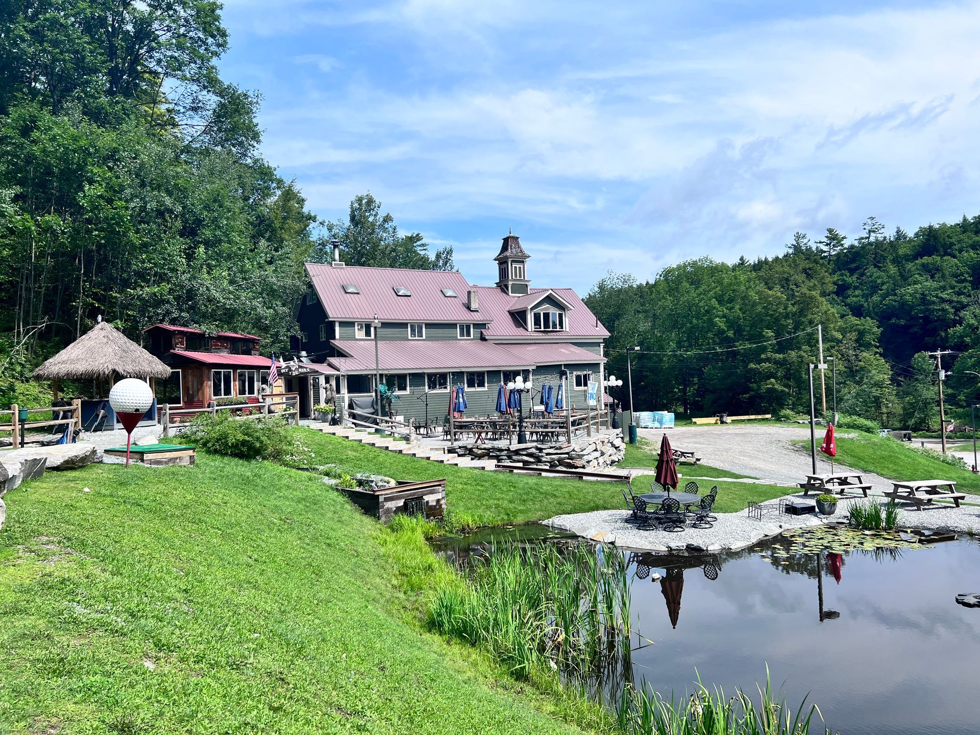 A large house is sitting on top of a hill next to a pond.