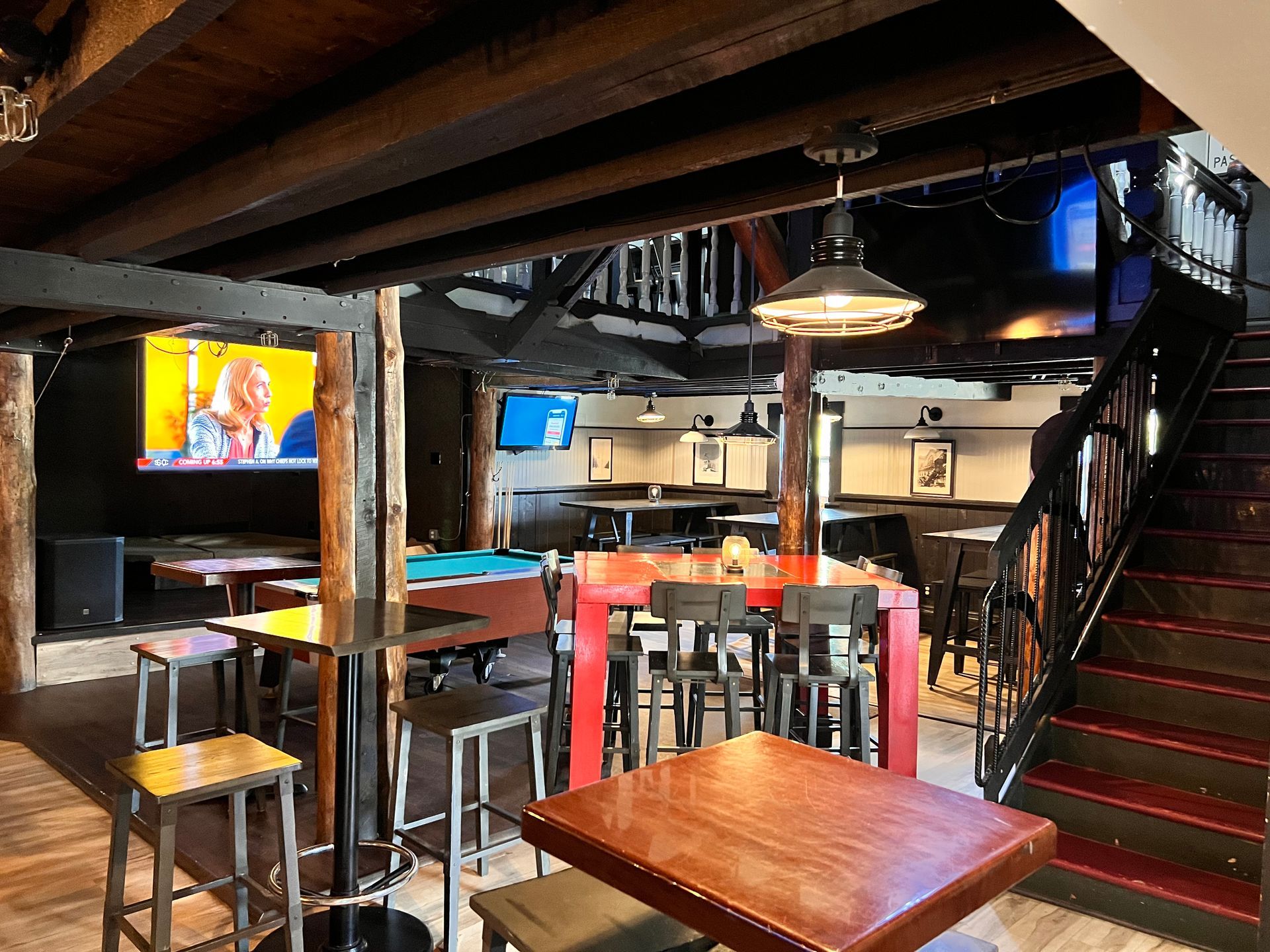 A bar with tables and stools and a pool table.