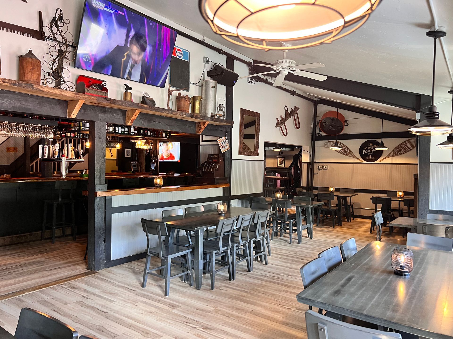 A restaurant with tables and chairs and a television on the wall.