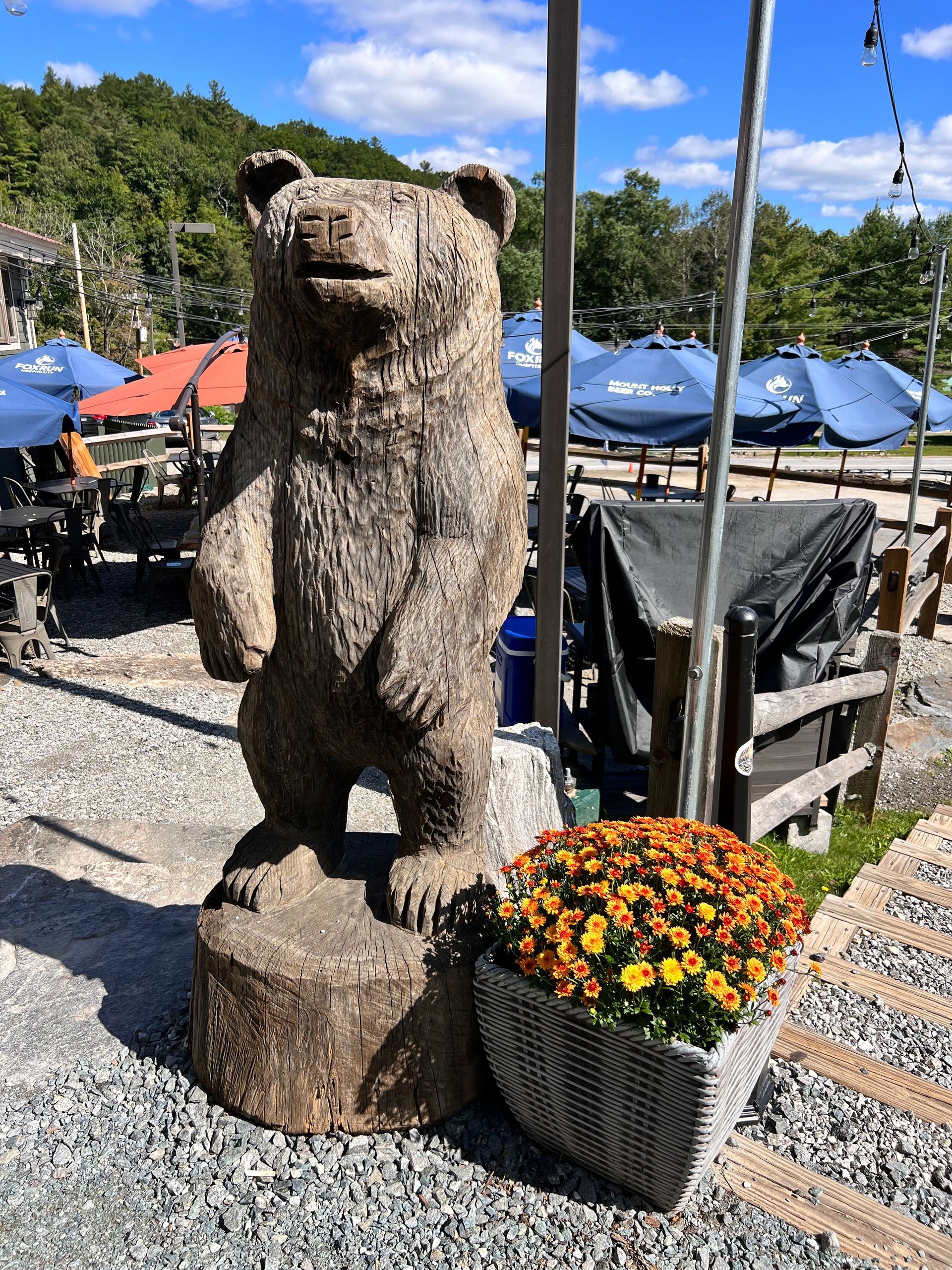 A statue of a bear is standing next to a basket of flowers.