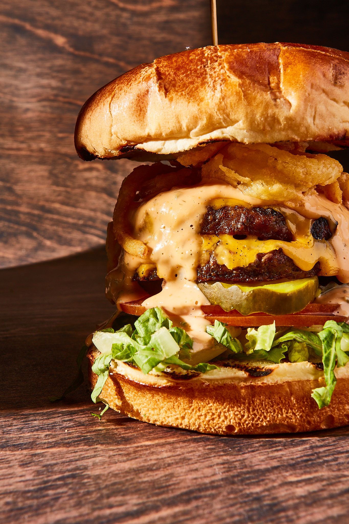 A close up of a hamburger on a wooden table.