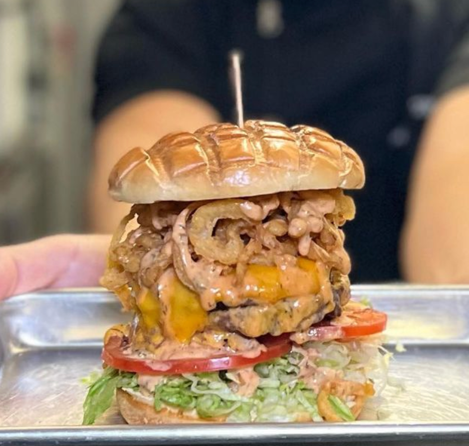 A person is holding a hamburger with a toothpick in it