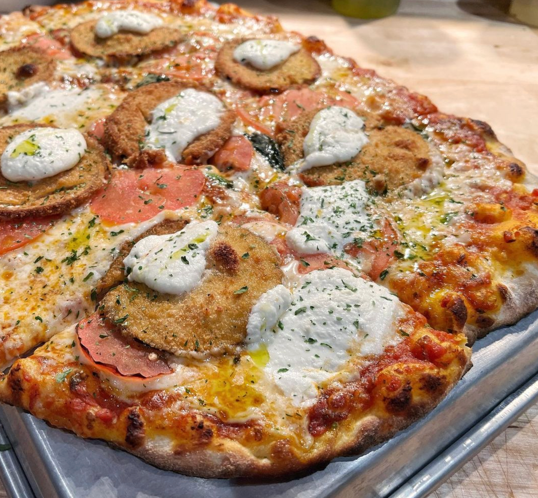 A pizza with a lot of toppings on it is on a tray on a table.