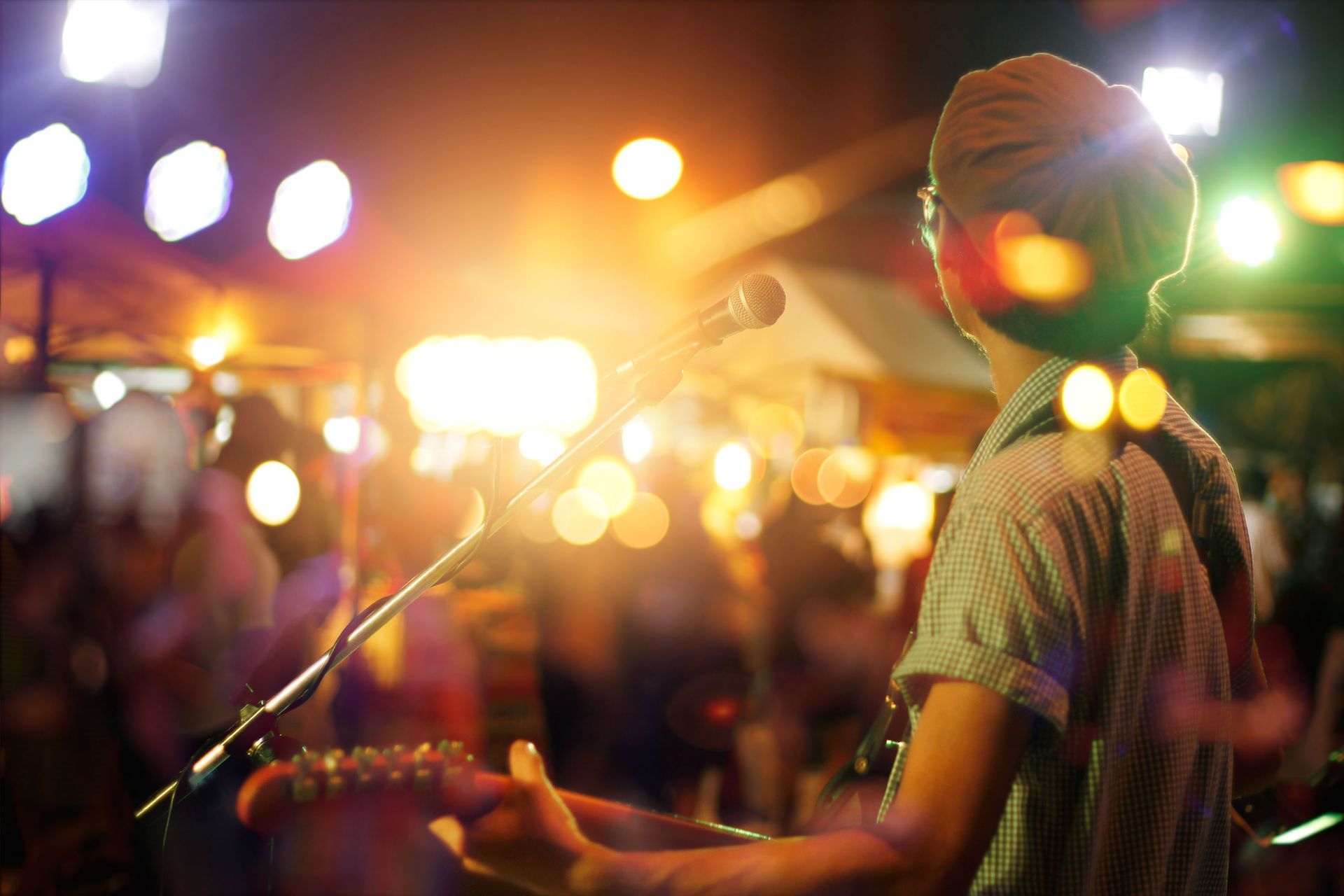 A man is playing a guitar and singing into a microphone at a concert.
