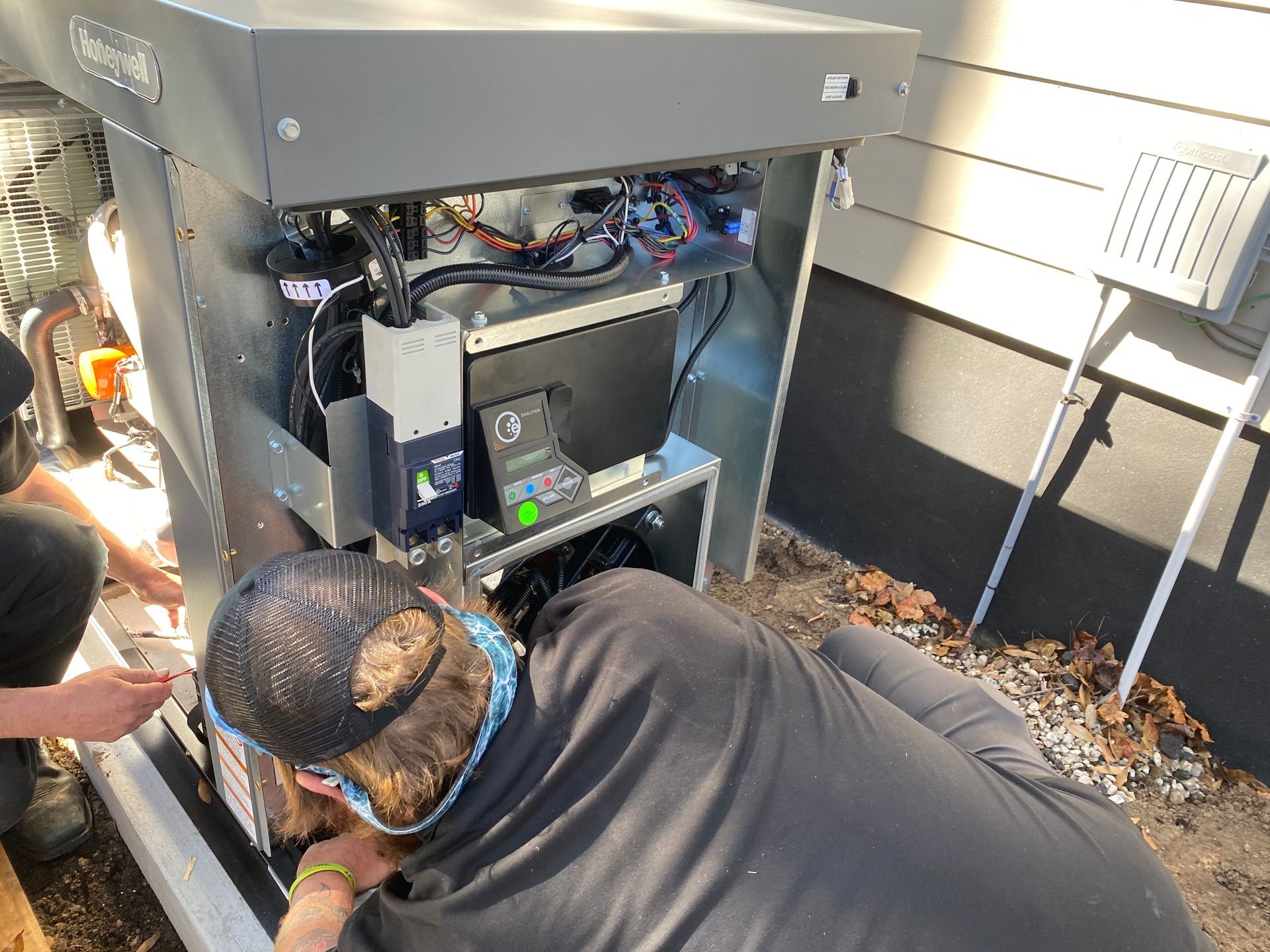 A man is working on an ac install outside of a house.