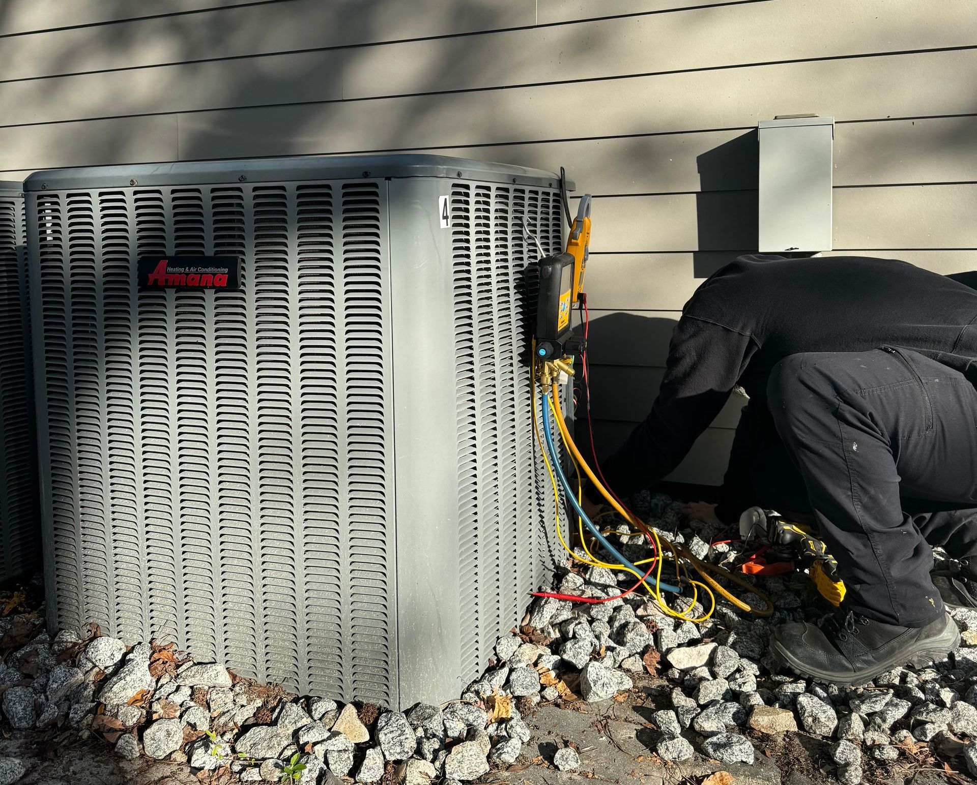 A man is working on an air conditioner outside of a house.