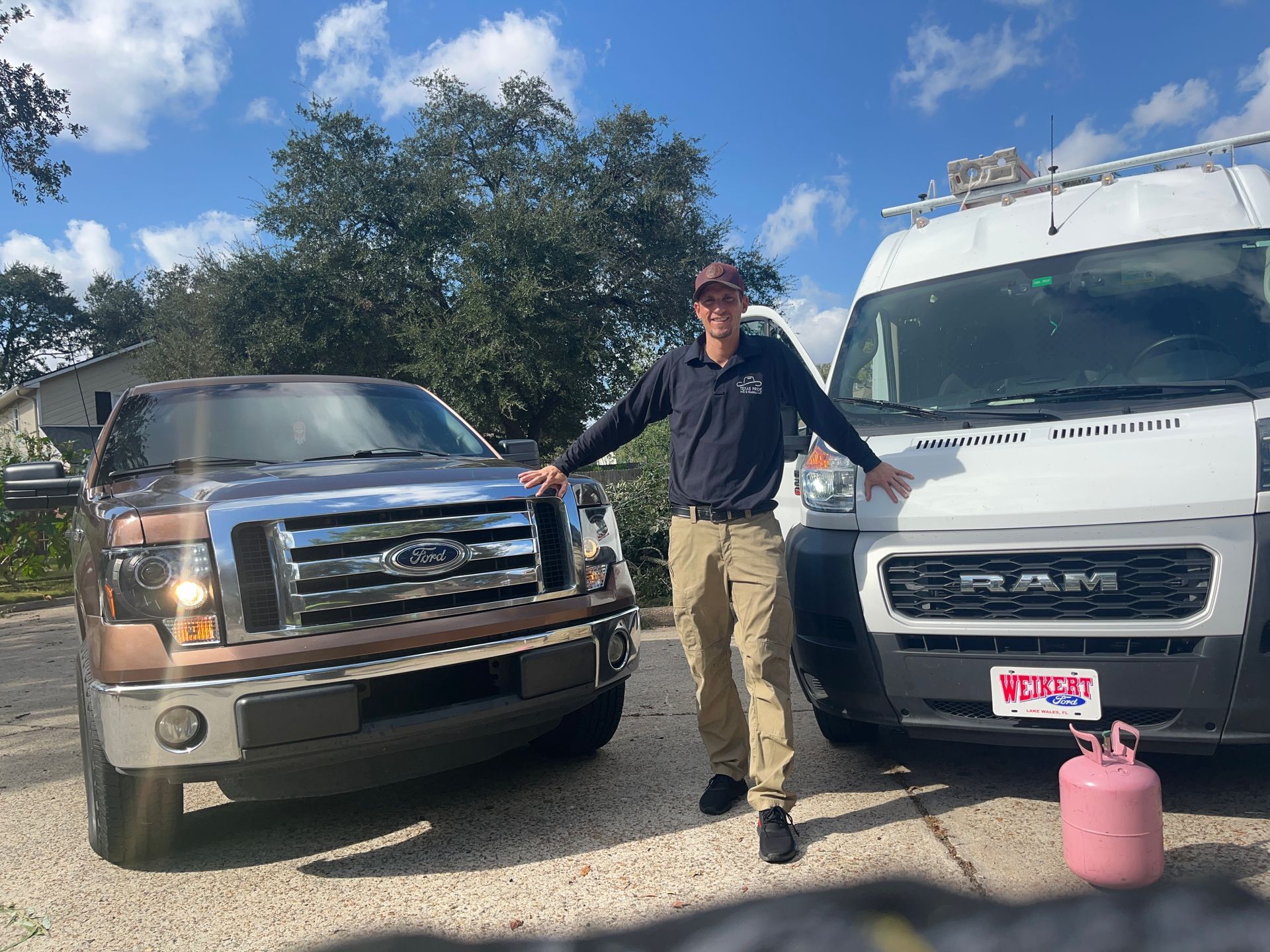 Technician from Texas Comfort Pros AC standing in front of 2 work trucks
