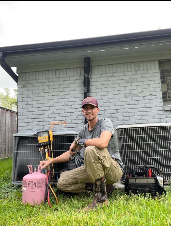A man is kneeling down in front of an air conditioner.