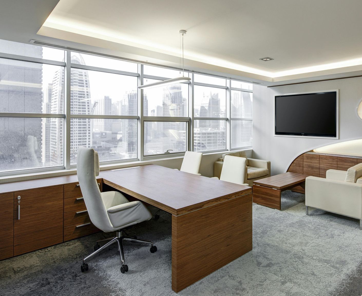 An office with a desk and chairs and a flat screen tv