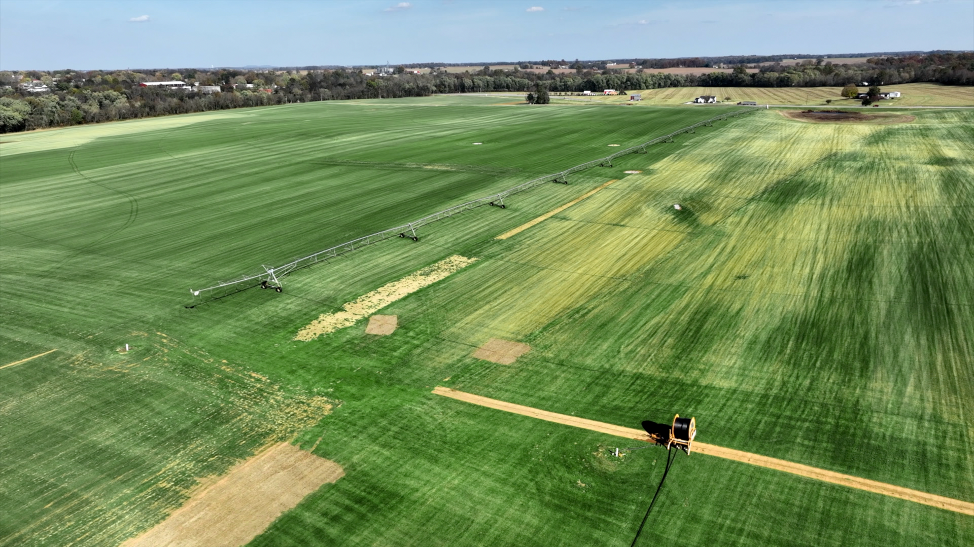 An aerial view of a large green field with a road going through it.