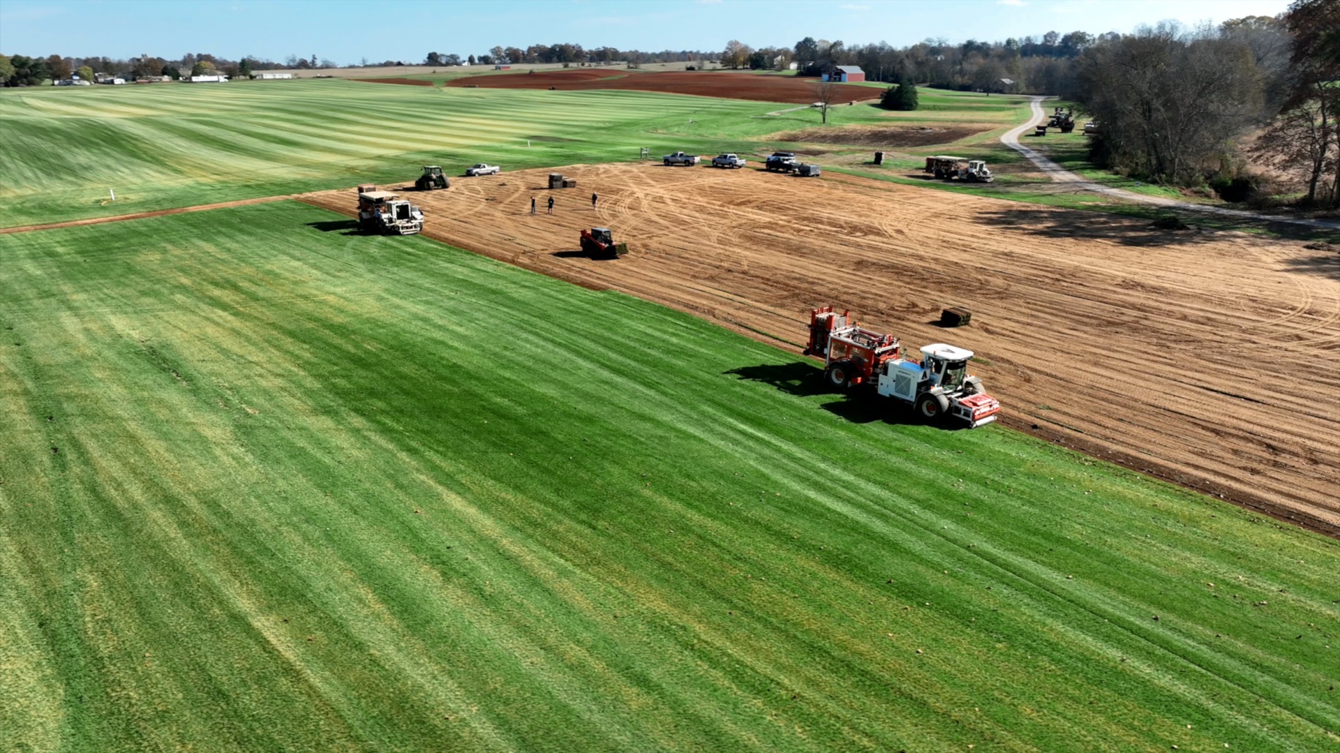An aerial view of a tractor plowing a field of grass.