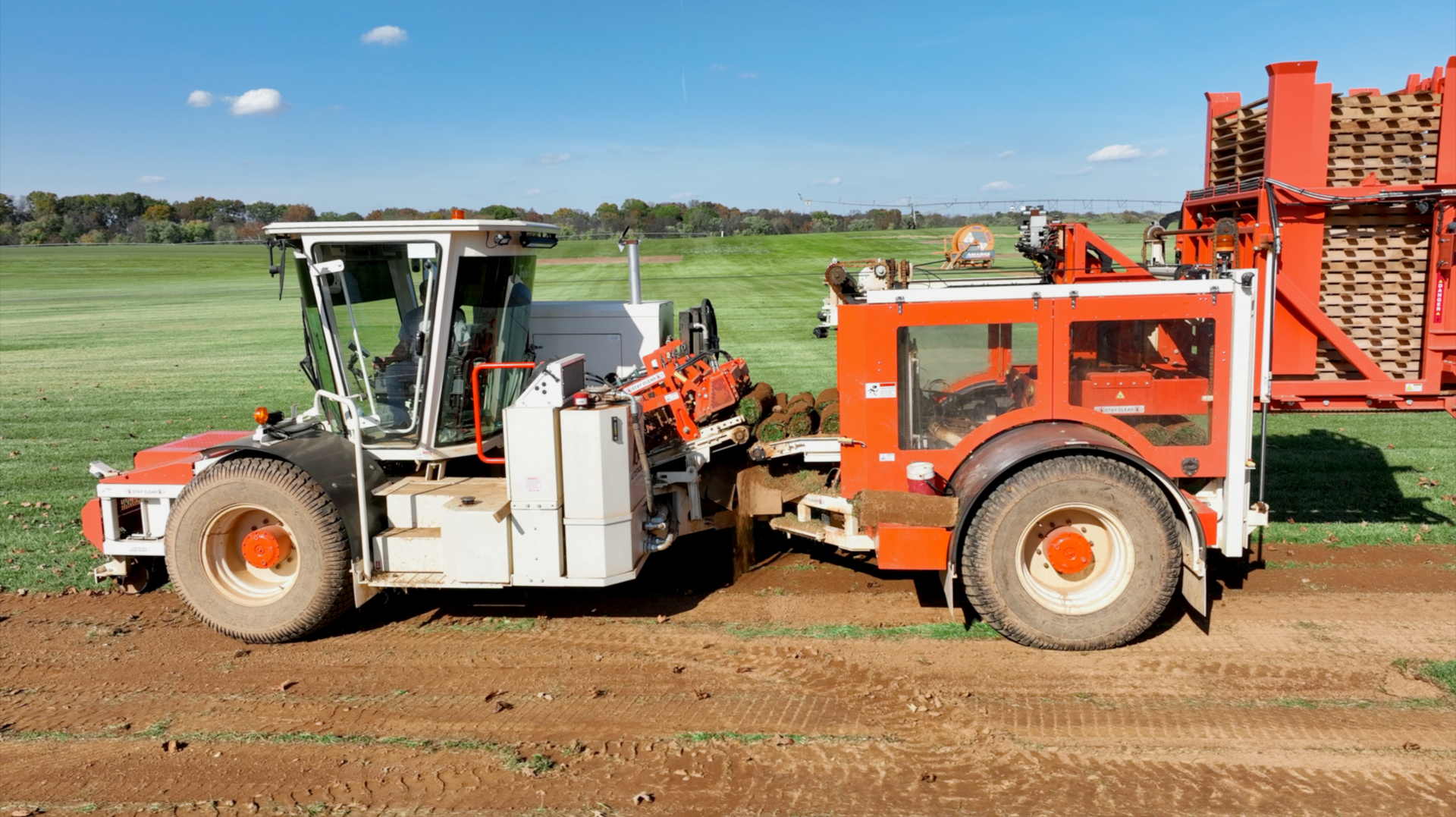 A red and white tractor is pulling a trailer in a field.