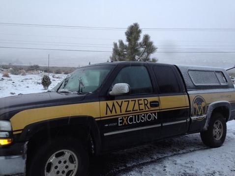A black and yellow truck with the word myzzer on the side is parked in the snow.