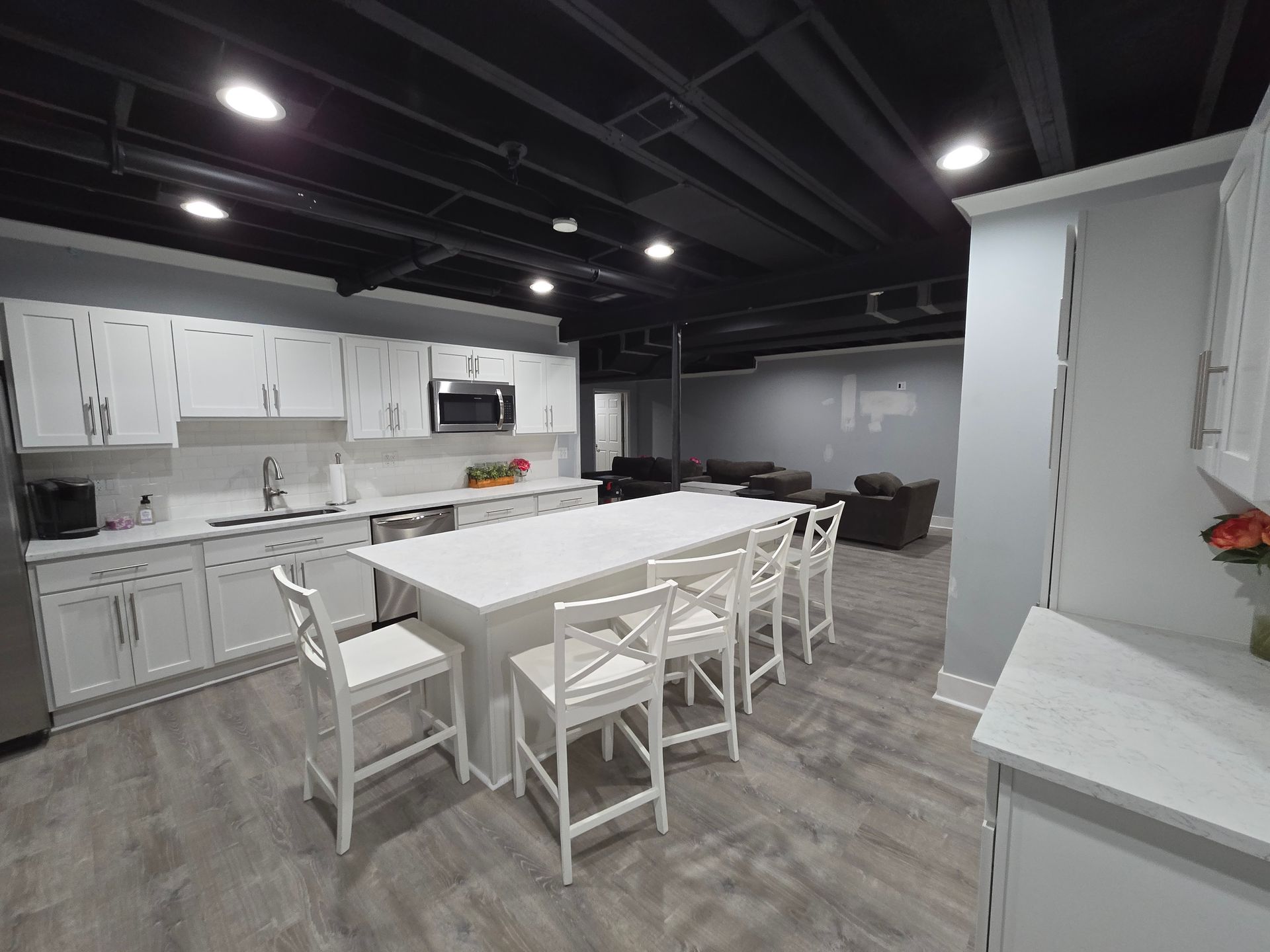 Modern kitchen with white cabinets, island dining table, and gray wood flooring