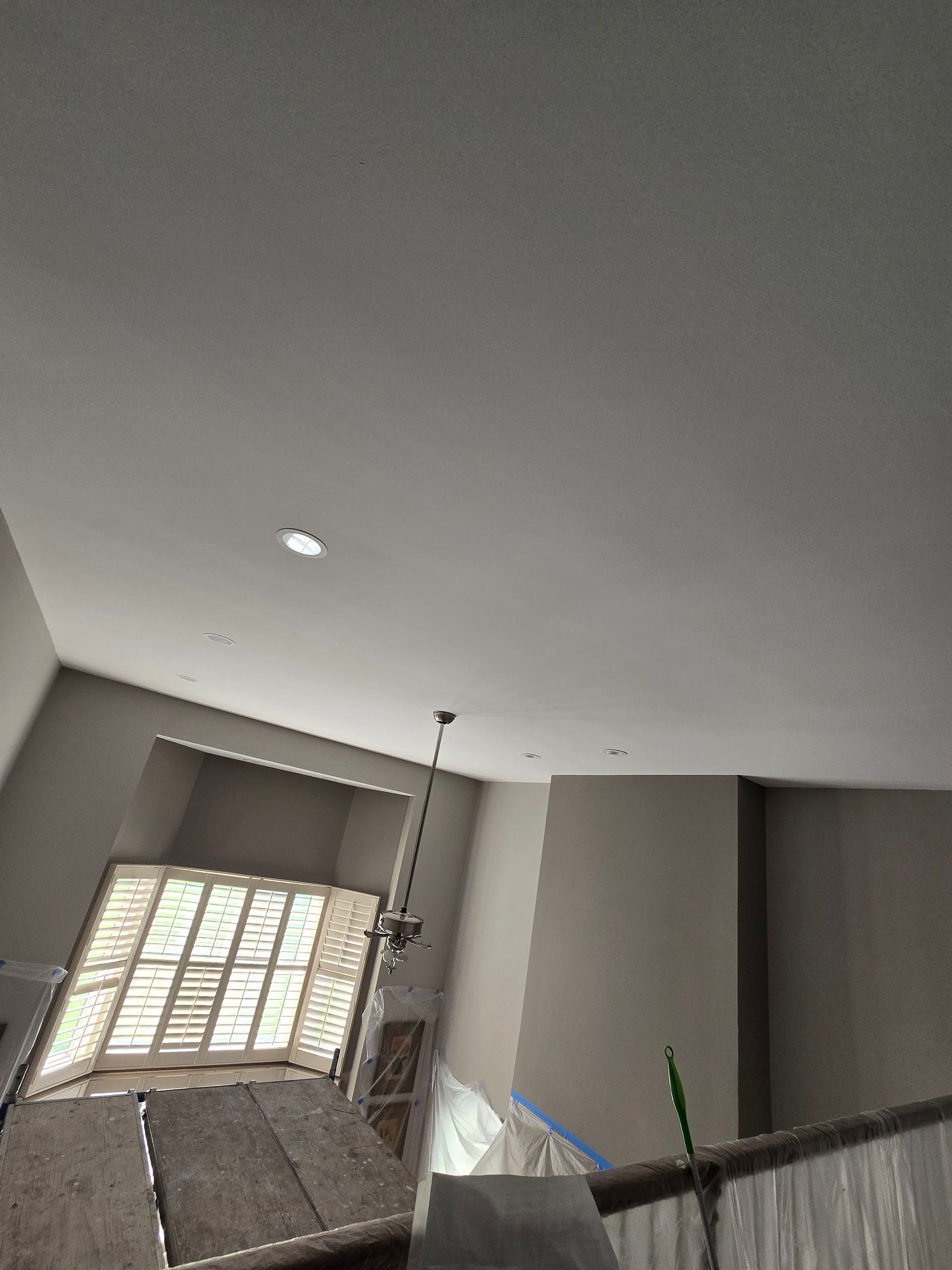 Interior stairwell with gray walls, white ceiling, and window blinds letting in sunlight.