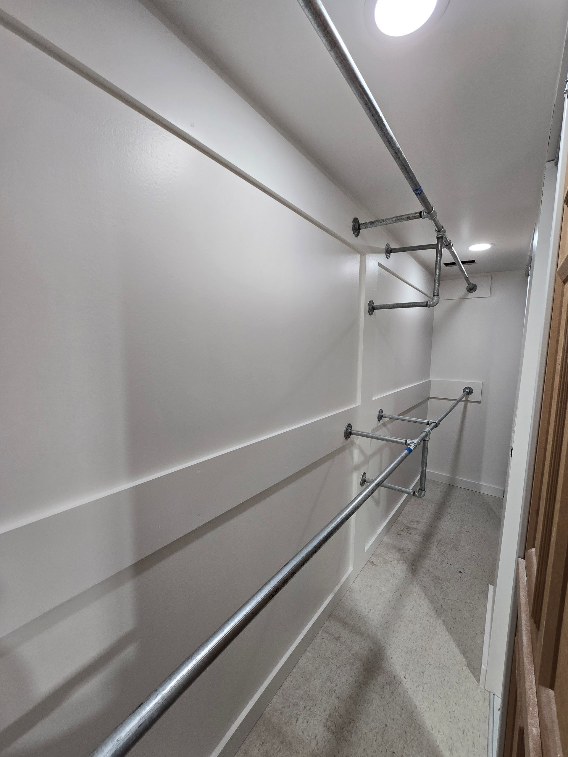Narrow hallway with metal handrails on both sides and overhead lights, likely a guided passageway