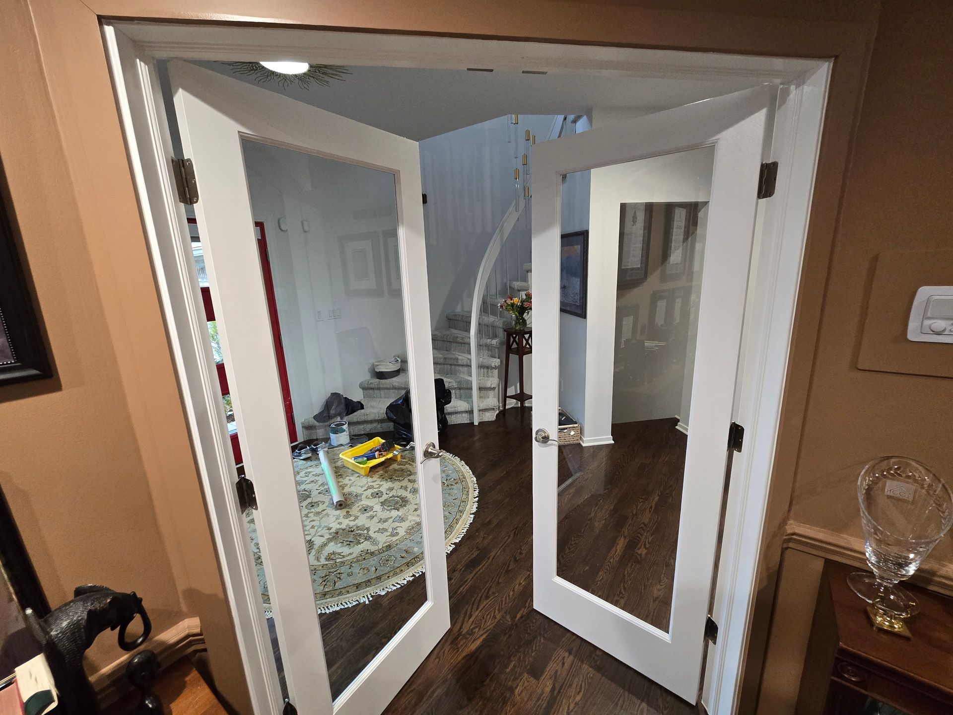Open mirrored closet doors in a bedroom, with a patterned rug and dark wood floor visible.
